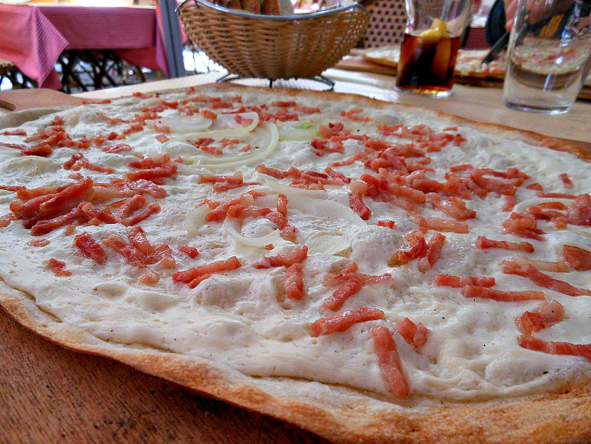 Tarte flambée is the Alsatian equivalent of pizza, served on a thin, crispy rectangular crust and topped with crème fraîche, white cheese, thinly sliced onions and lardons (a French-style bacon of sorts)