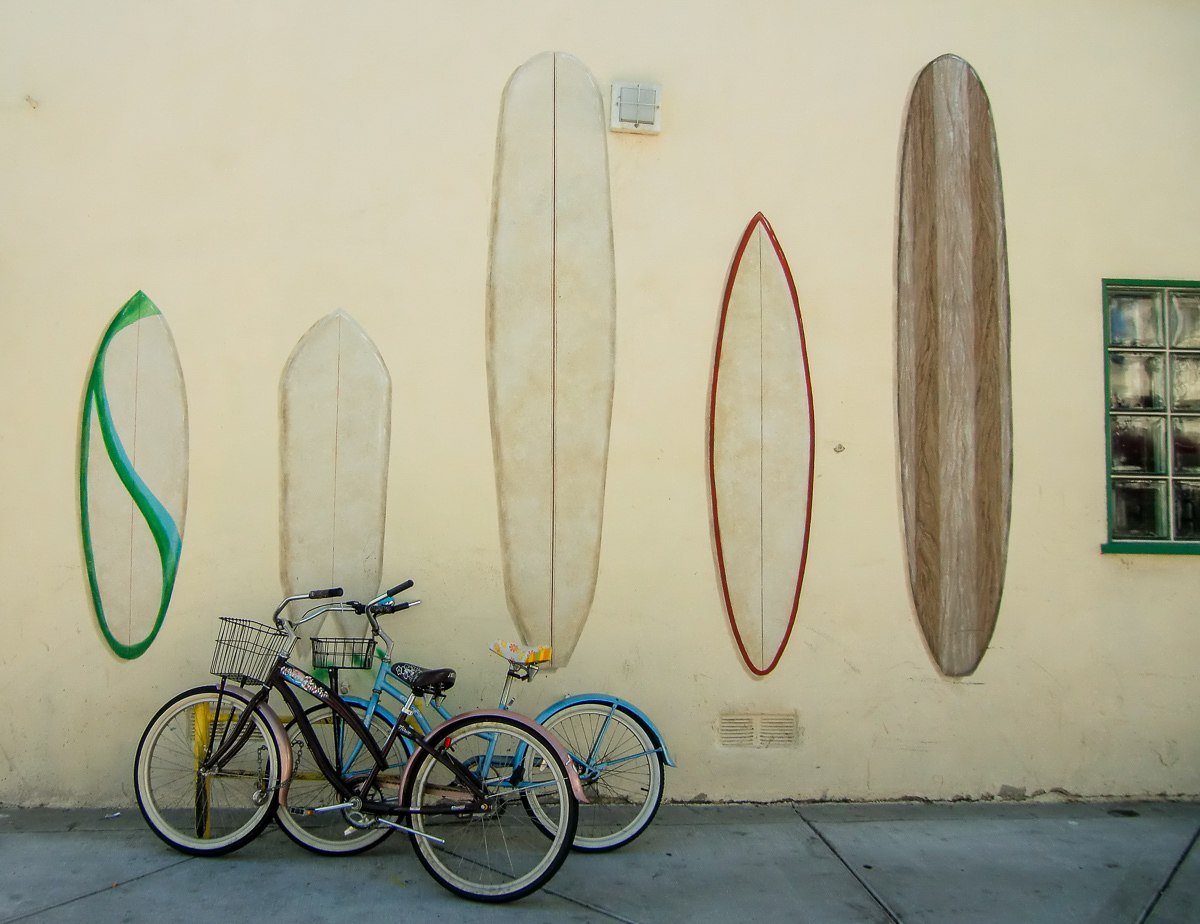 Beach cruisers in front of a surfboard mural in Huntington Beach, California