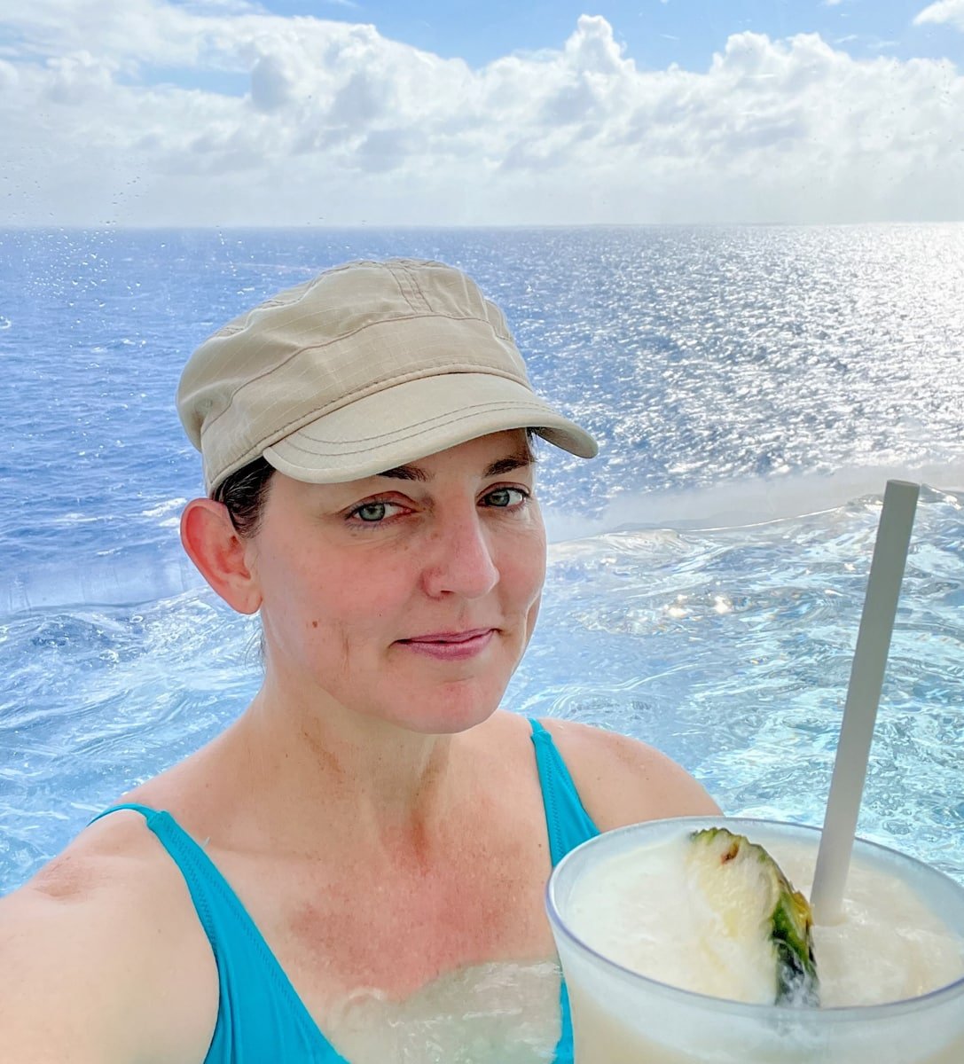 The Travel Mama enjoying a Virgin Piña Colada in an oceanfront hot tub on Wonder of the Seas 
