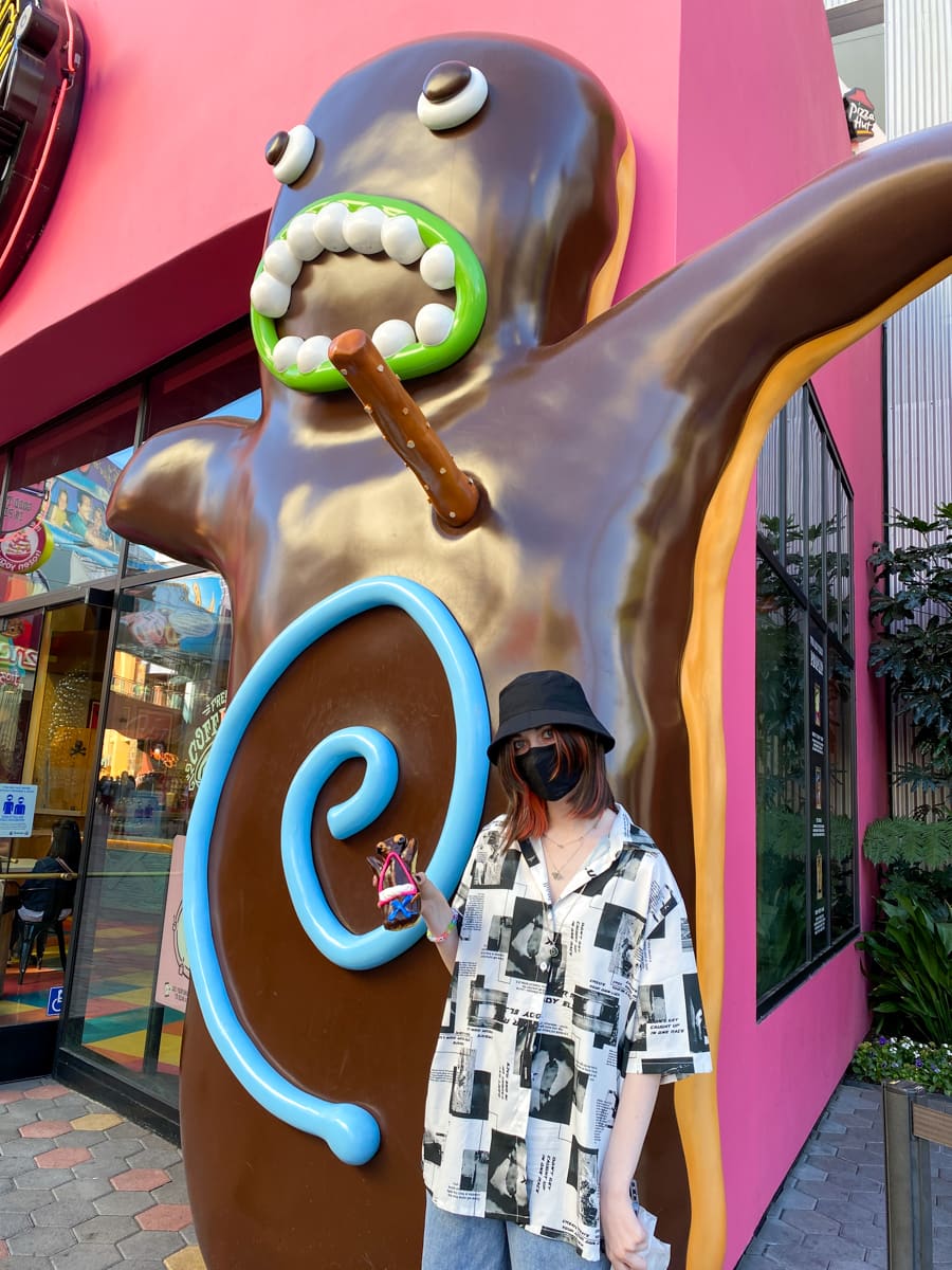 My daughter posing with a giant Voodoo Doll donut statue at Voodoo Doughnut