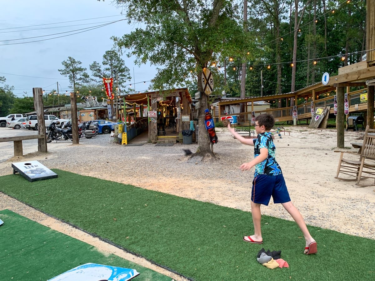 Kid playing cornhole at The Shed BBQ in Mississippi Gulf Coast